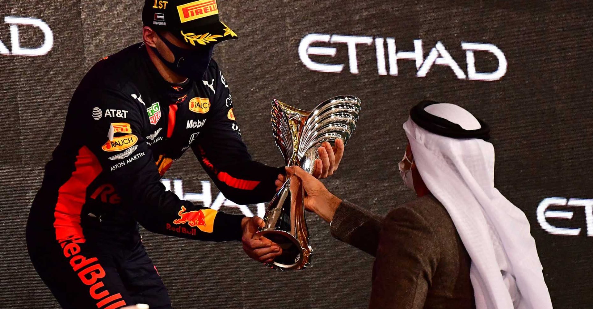 ABU DHABI, UNITED ARAB EMIRATES - DECEMBER 13: Race winner Max Verstappen of Netherlands and Red Bull Racing is presented with his trophy on the podium during the F1 Grand Prix of Abu Dhabi at Yas Marina Circuit on December 13, 2020 in Abu Dhabi, United Arab Emirates. (Photo by Giuseppe Cacace - Pool/Getty Images)