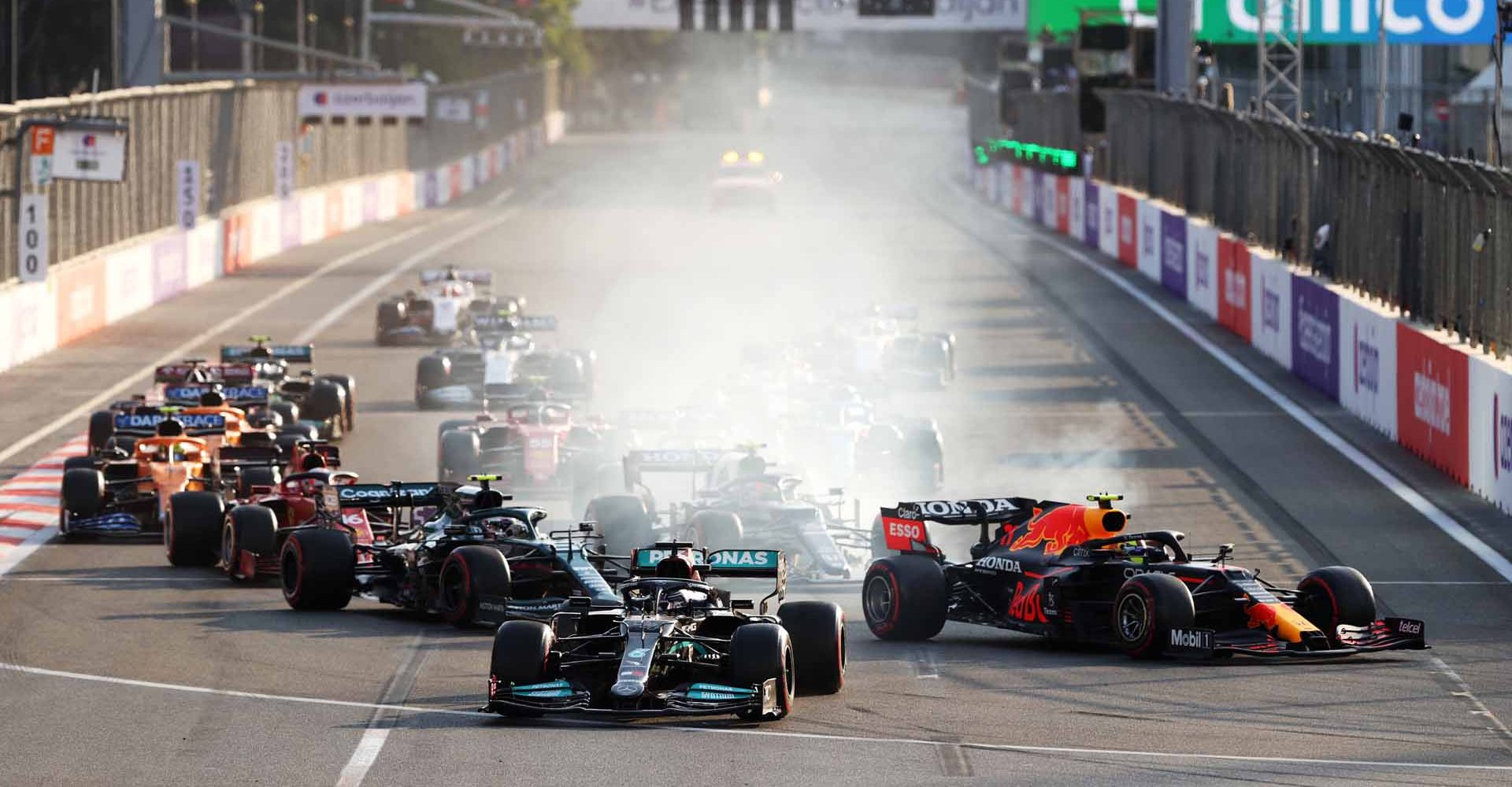 BAKU, AZERBAIJAN - JUNE 06: Lewis Hamilton of Great Britain driving the (44) Mercedes AMG Petronas F1 Team Mercedes W12 locks up under pressure from Sergio Perez of Mexico driving the (11) Red Bull Racing RB16B Honda into the first corner after the restart following a red flag period during the F1 Grand Prix of Azerbaijan at Baku City Circuit on June 06, 2021 in Baku, Azerbaijan. (Photo by Clive Rose/Getty Images)