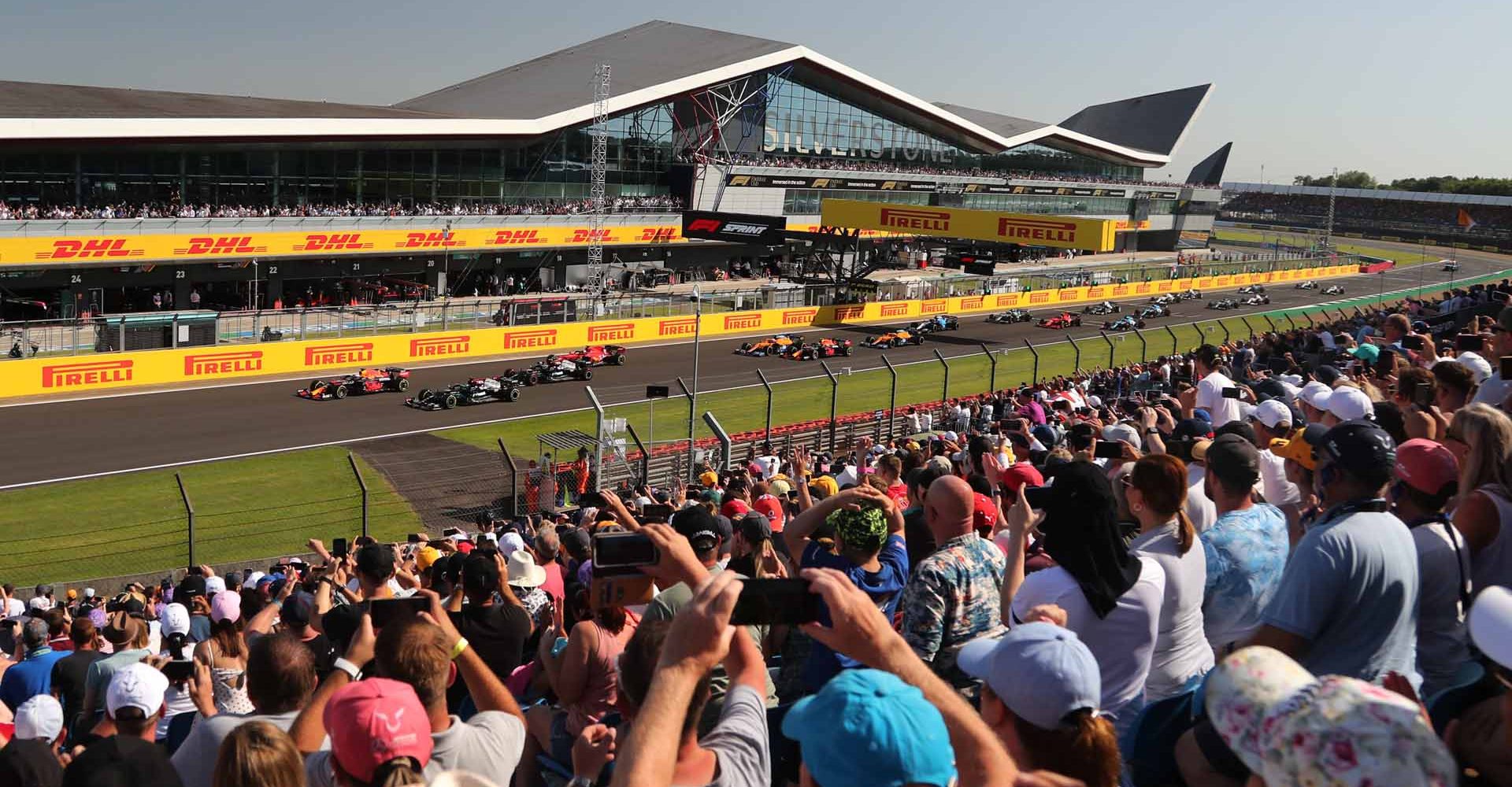 SILVERSTONE CIRCUIT, UNITED KINGDOM - JULY 17: Max Verstappen, Red Bull Racing RB16B, leads Sir Lewis Hamilton, Mercedes W12, Valtteri Bottas, Mercedes W12, Charles Leclerc, Ferrari SF21, and the rest of the field at the start during the British GP at Silverstone Circuit on Saturday July 17, 2021 in Northamptonshire, United Kingdom. (Photo by JEP / LAT Images)