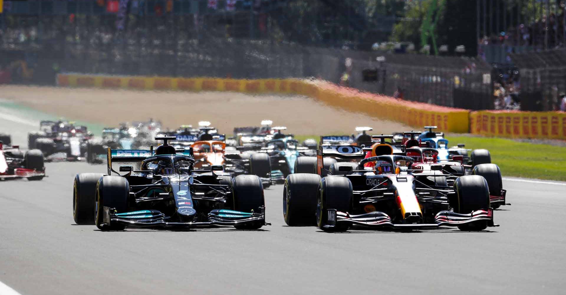 SILVERSTONE CIRCUIT, UNITED KINGDOM - JULY 18: Max Verstappen, Red Bull Racing RB16B leads Sir Lewis Hamilton, Mercedes W12 at the start of the race during the British GP at Silverstone Circuit on Sunday July 18, 2021 in Northamptonshire, United Kingdom. (Photo by Steven Tee / LAT Images)