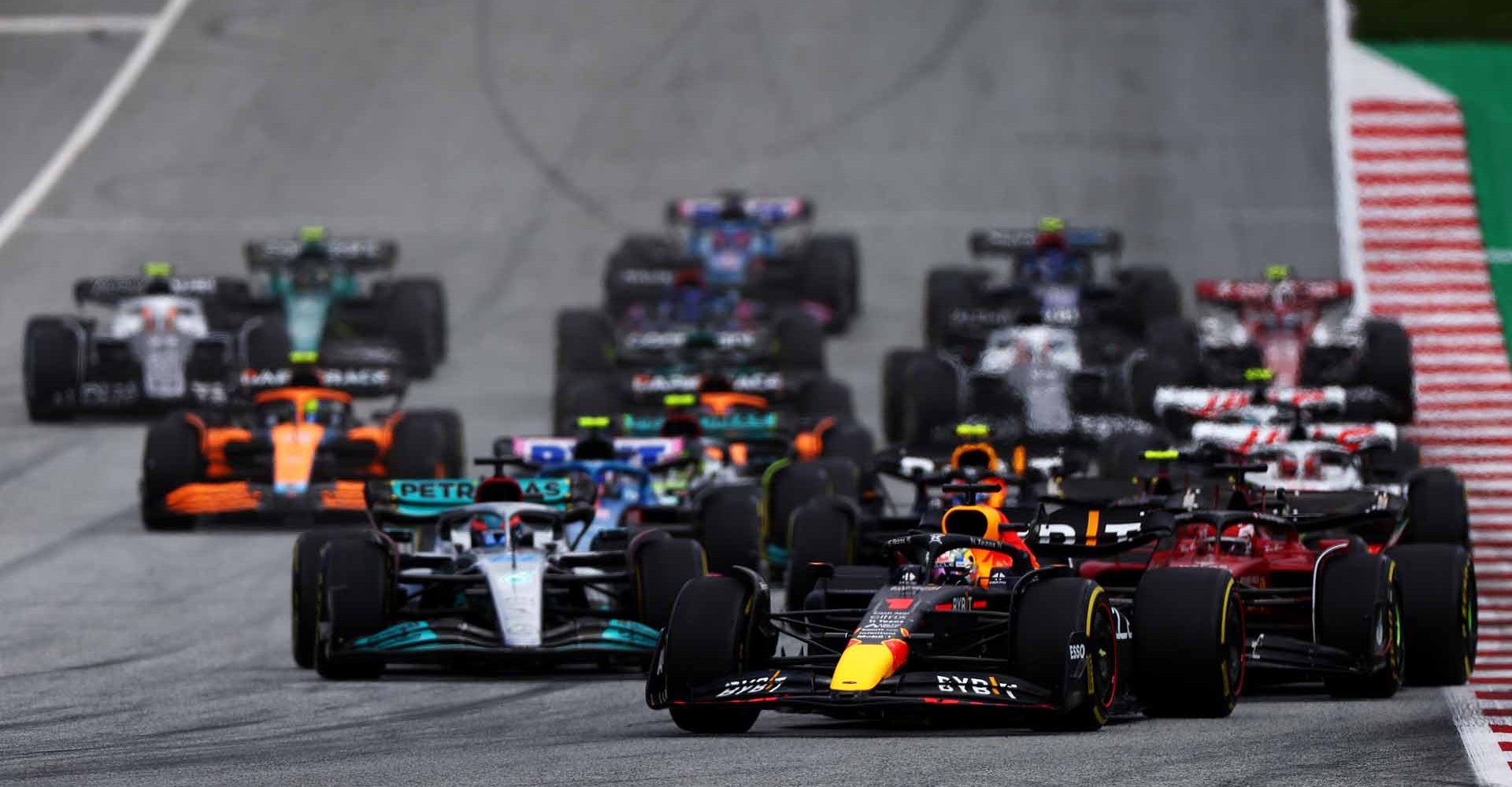 SPIELBERG, AUSTRIA - JULY 10: Max Verstappen of the Netherlands driving the (1) Oracle Red Bull Racing RB18 leads Charles Leclerc of Monaco driving the (16) Ferrari F1-75 and the rest of the field into turn one at the start during the F1 Grand Prix of Austria at Red Bull Ring on July 10, 2022 in Spielberg, Austria. (Photo by Bryn Lennon/Getty Images)