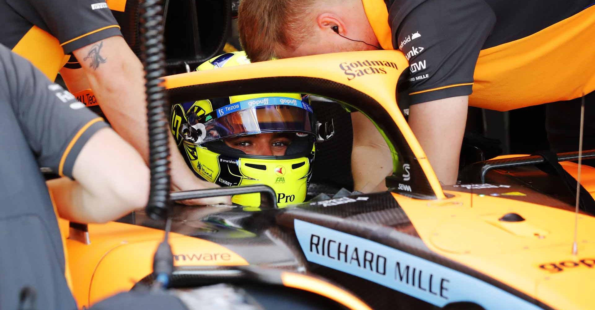 Lando Norris, McLaren, is attended to by mechanics in cockpit