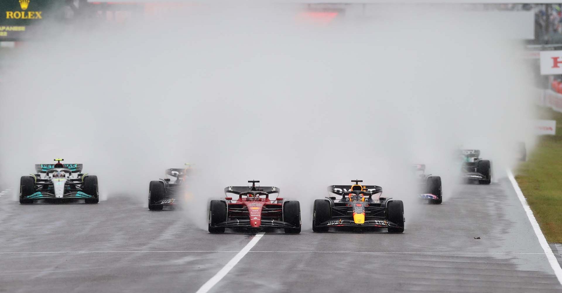 SUZUKA, JAPAN - OCTOBER 09: Max Verstappen of the Netherlands driving the (1) Oracle Red Bull Racing RB18 and Charles Leclerc of Monaco driving the (16) Ferrari F1-75 battle for track position into turn one at the start during the F1 Grand Prix of Japan at Suzuka International Racing Course on October 09, 2022 in Suzuka, Japan. (Photo by Peter Fox/Getty Images)