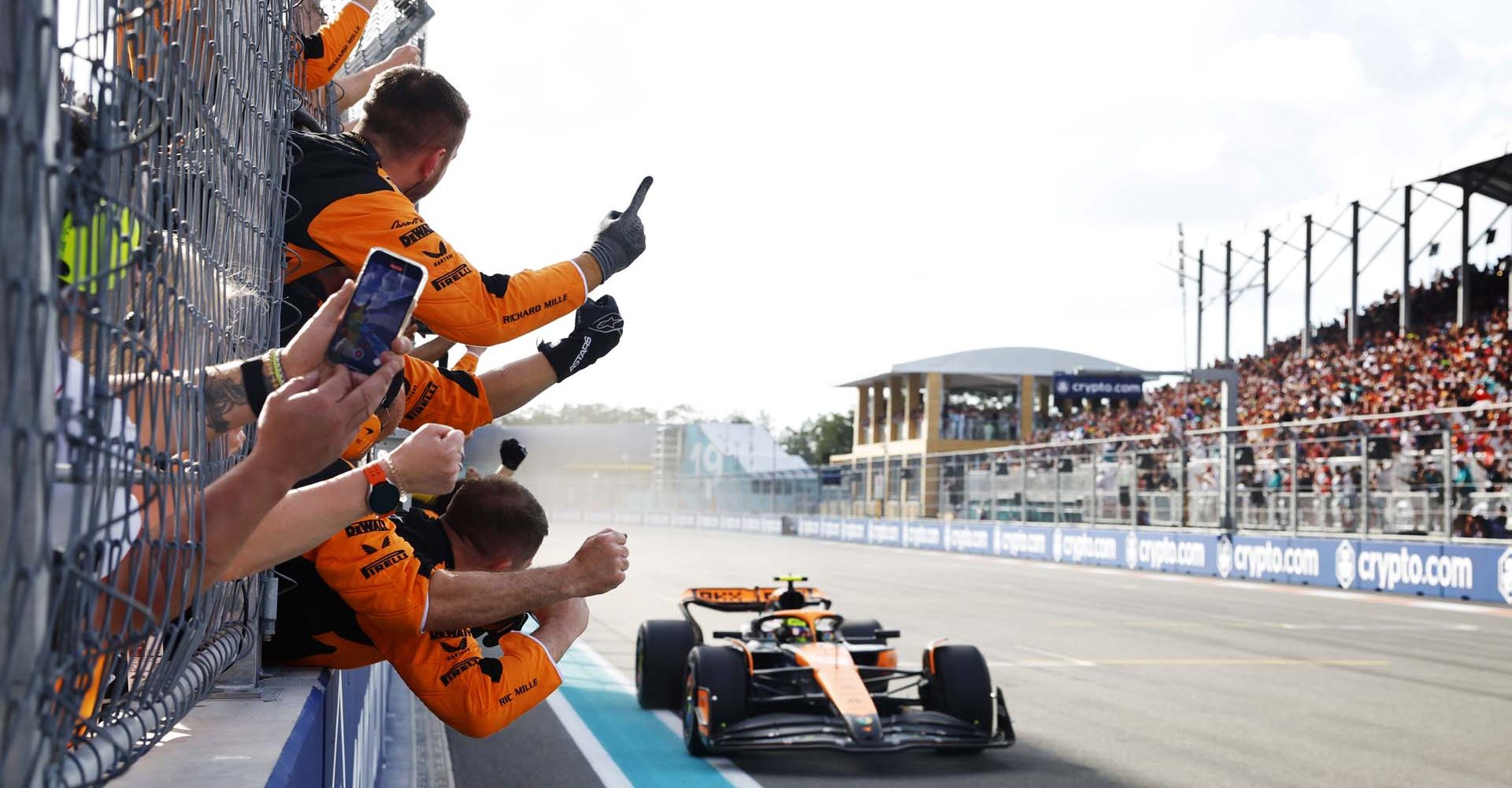 Lando Norris, McLaren MCL38, 1st position, crosses the line to cheers from his team on the pit wall