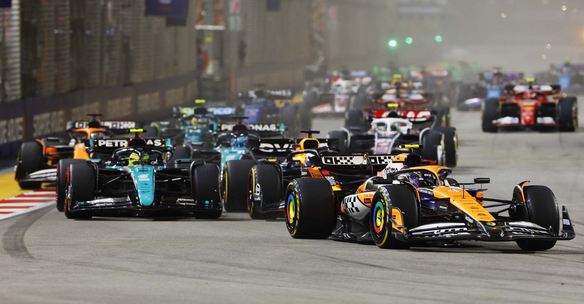 MARINA BAY STREET CIRCUIT, SINGAPORE - SEPTEMBER 22: Lando Norris, McLaren MCL38, leads Max Verstappen, Red Bull Racing RB20, Sir Lewis Hamilton, Mercedes F1 W15, George Russell, Mercedes F1 W15, and the rest of the field at the start during the Singapore GP at Marina Bay Street Circuit on Sunday September 22, 2024 in Singapore, Singapore. (Photo by Steven Tee / LAT Images)