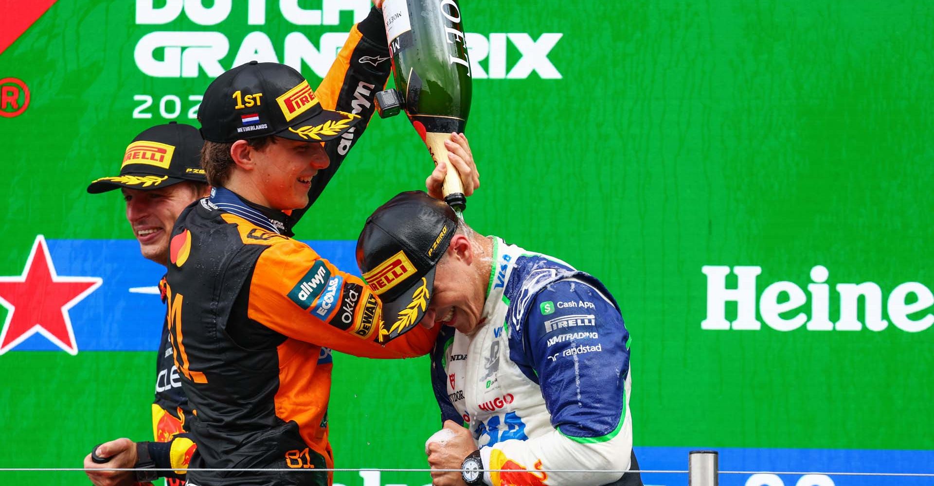 ZANDVOORT, NETHERLANDS - AUGUST 31: Race winner Oscar Piastri of Australia and McLaren pours champagne over Third placed Isack Hadjar of France and Visa Cash App Racing Bulls on the podium during the F1 Grand Prix of Netherlands at Circuit Zandvoort on August 31, 2025 in Zandvoort, Netherlands. (Photo by Clive Rose/Getty Images)