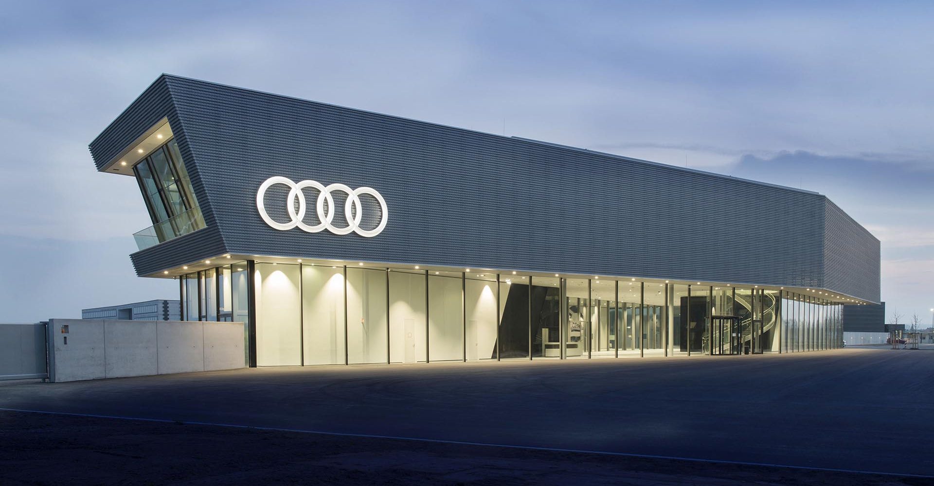 Audi Neuburg is an integral component of the global investment strategy of AUDI AG. The 47-hectare site lies west of Ingolstadt, just 18 km (11.2 mi) from Audi headquarters.
The grounds are the home of the new Audi driving experience center. Beginning in May 2014, ambitious drivers can experience the Audi brand during driver and safety training courses both on-road and off-road. 
The Motorsport Competence Center, the new headquarters of Audi Sport, is also being constructed here. From fall 2014, all motorsport racing cars will be developed, designed and built here.

Here:
The central customer building at the Audi Neuburg site offers presentation spaces
on multiple floors as well as a restaurant. From the terrace, customers enjoy
a panoramic view of the entire site and the cars on the tracks.