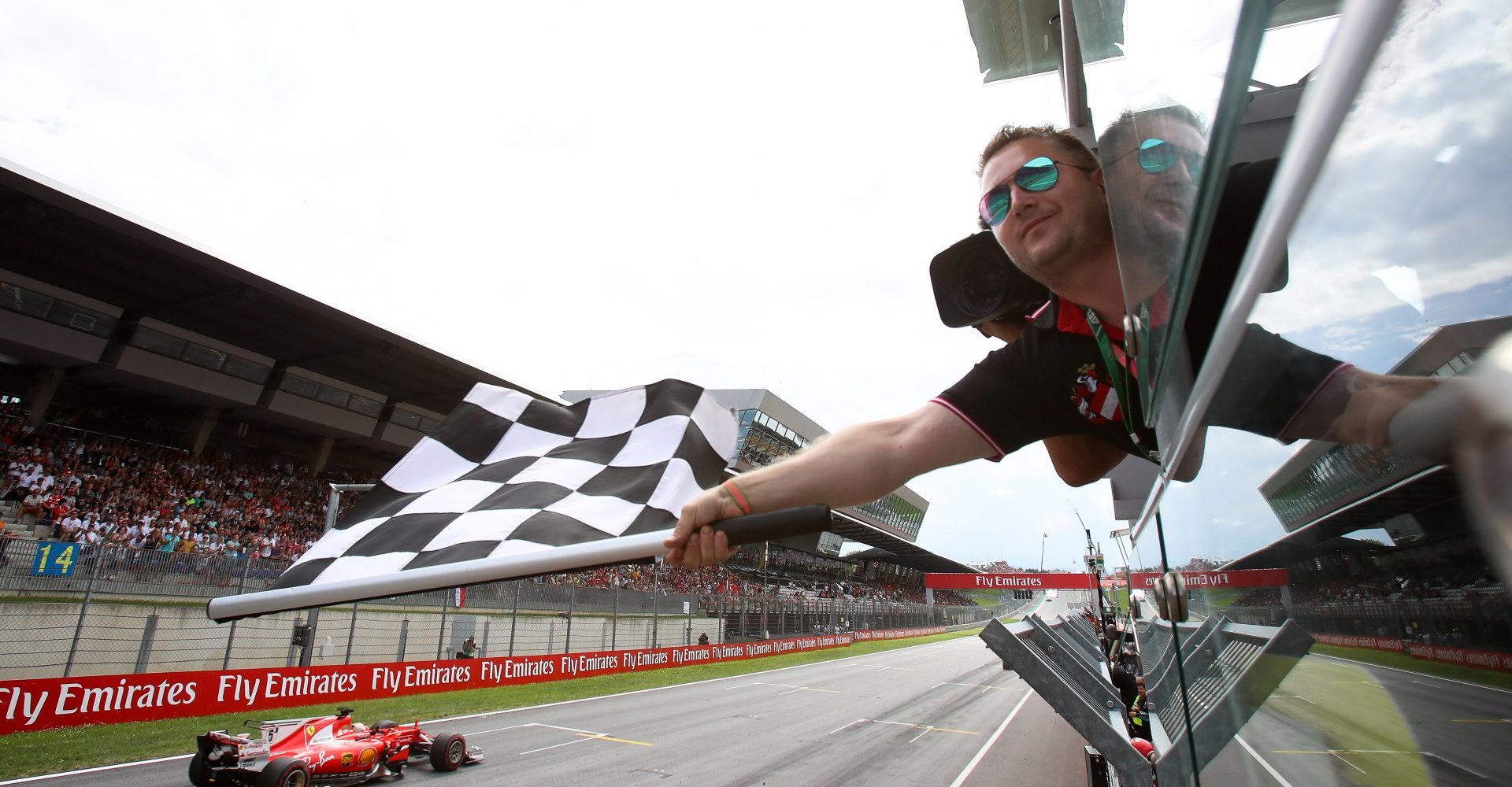 SPIELBERG,AUSTRIA,09.JUL.17 - MOTORSPORTS, FORMULA 1 - Grand Prix of Austria, Red Bull Ring, award ceremony. Image shows the flagman with the chequered flag and Sebastian Vettel (GER/ Ferrari). Photo: GEPA pictures/ Christian Walgram - For editorial use only. Image is free of charge.