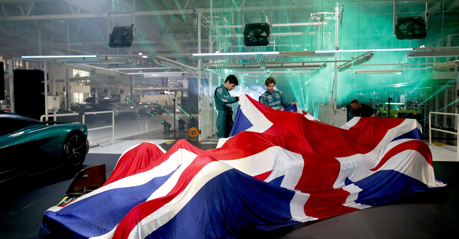 Sebastian Vettel, Aston Martin, and Lance Stroll, Aston Martin, lift the covers on a Union Flag to unveil the Aston Martin AMR22